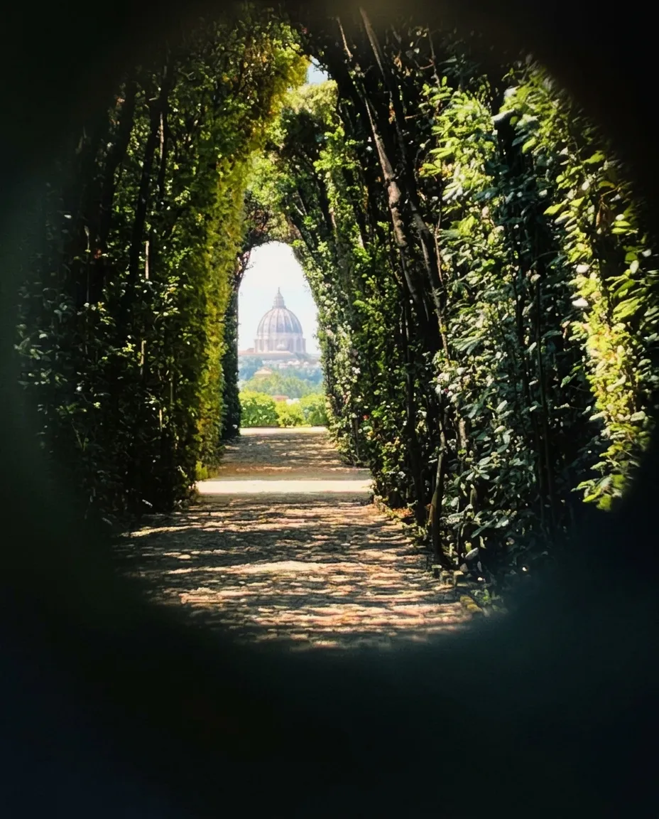 The dome of St Peter's seen through the keyhole of the Priory of Malta, framed by a tunnel of hedges